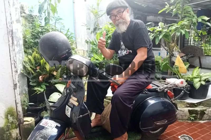 Husnawi duduk di Vespanya di depan GaleriKU (foto: Norben Syukur/PARBOABOA)